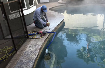 This image shows a man resurfacing a pool deck