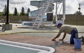 This image shows a man repairing cracks in a pool deck.